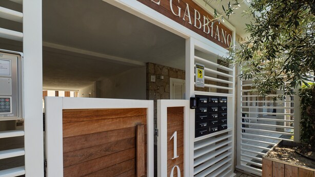 En hotelindgang med en trædør, et skilt med 'GABBIANO' og nummeret '10' på væggen.