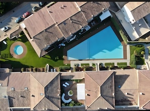 Vista aérea de una zona residencial con piscina, varios tejados y un jardín circular.