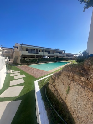 Ein modernes Gebäude mit Schwimmbad, gepflasterter Terrasse und angelegtem Garten.