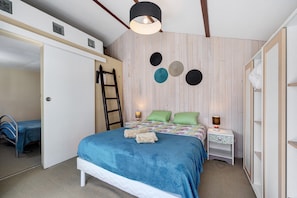 Un dormitorio con cama, mesita de noche, escalera y armario.