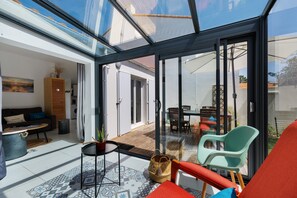 A modern living space with a glass ceiling, a dining area, and a cozy seating arrangement. - Holiday Home 'La Petite Vague' with Private Terrace and Private Garden (Saint-Hilaire-de-Riez)