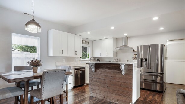 A modern kitchen with white cabinets, stainless steel appliances, and a wooden island. - Pet haven near Eugene | Fenced backyard (Creswell)
