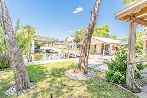 A rustic outdoor area with a covered seating area, a small dock, and a pond.
