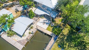 An aerial view of a property with multiple buildings, a dock, and a small water body.