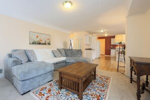Ein Wohnzimmer mit grauem Sofa, einem Holztisch und einem Teppich mit Muster.