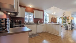 Uma cozinha moderna com armários brancos, uma ilha central e um espaço de refeições com um lustre.
