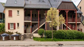 Kaksikerroksinen rakennus, jossa on parveke, portaikko ja pieni puu etupihalla.