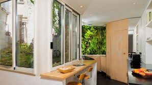 Eine moderne Küche mit einem großen Fenster, einer Holz Arbeitsplatte und einer integrierten vertikalen Begrünung.