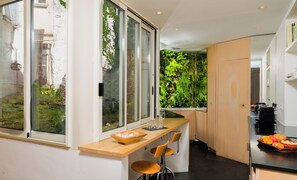 Eine moderne Küche mit einem großen Fenster, einer Holz Arbeitsplatte und einer integrierten vertikalen Begrünung.