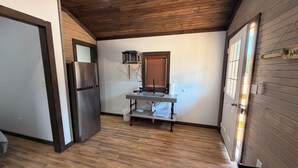 Una cocina compacta con microondas integrado, refrigerador de acero inoxidable y techo de madera.