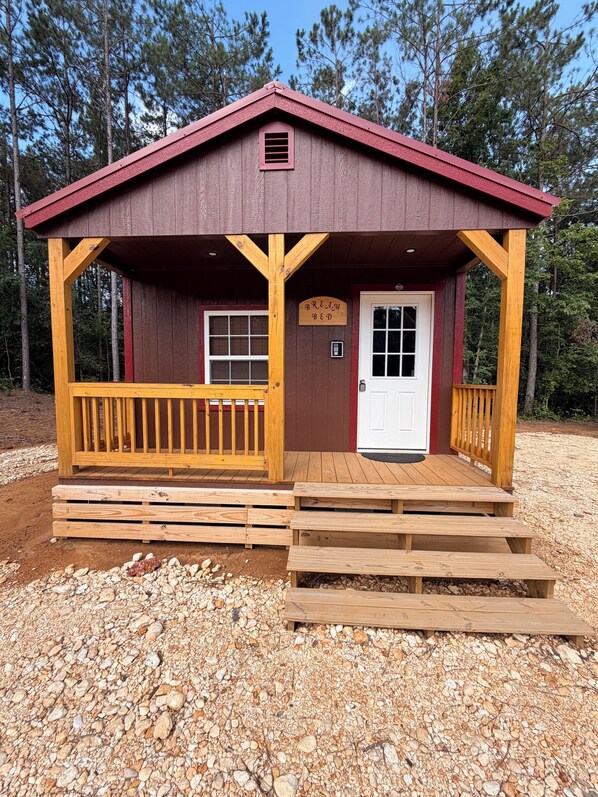 A wooden cabin with a porch, a door, and a sign that reads 'BREWM BED.'