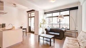 Un espacio moderno para vivir con una isla de cocina, un sofá, una mesa de centro y un amplio ventanal con vistas.