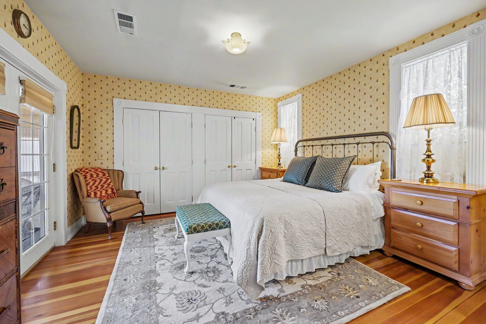 A bedroom with a bed, a chair, a dresser, a lamp, and a window.