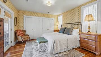 A bedroom with a bed, a chair, a dresser, a lamp, and a window.