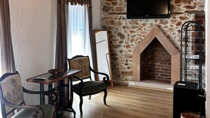 A room with a wooden ceiling, stone wall, fireplace, television, and antique furniture. - Chori Avlu Küçükköy (Küçükköy)