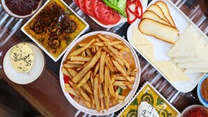 A variety of food items including olives, hummus, fries, and sliced cucumbers arranged on a table. - Chori Avlu Küçükköy (Küçükköy)