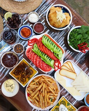 Svariati cibi disposti su un tavolo, tra cui olive, hummus, patatine fritte e cetrioli a fette.