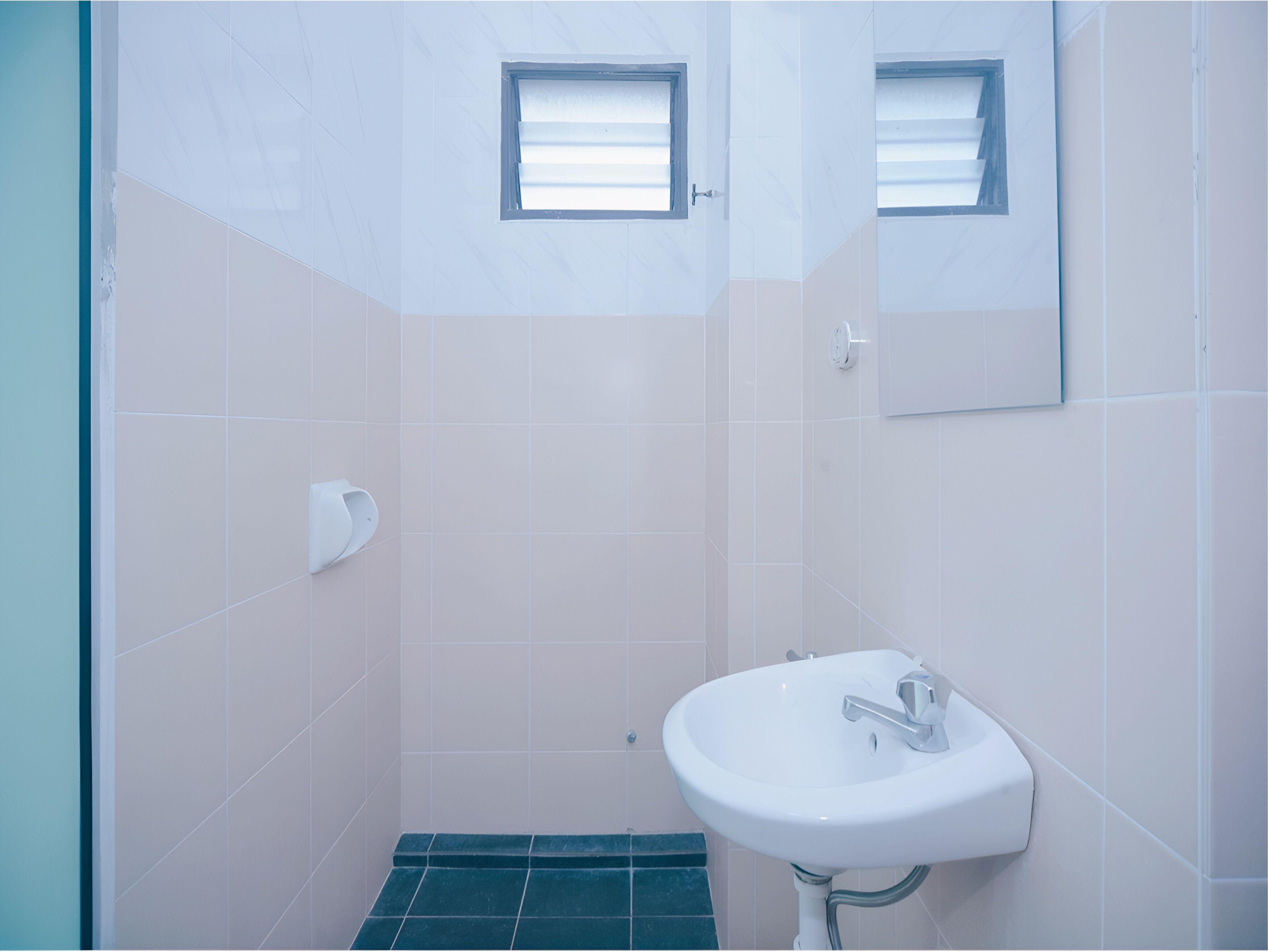 A bathroom with a white sink, a mirror, and a window.