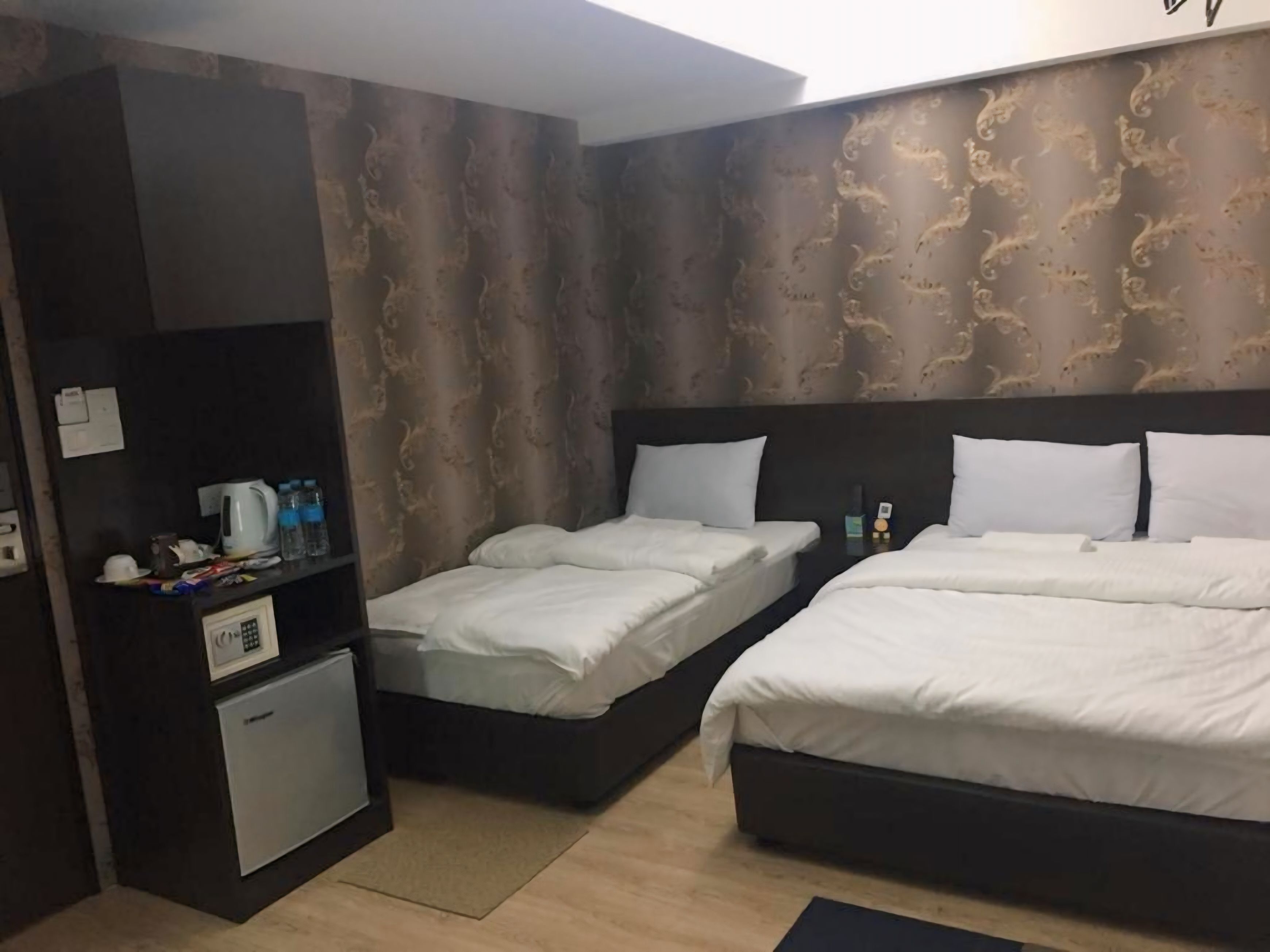Habitación de hotel con dos camas, un escritorio pequeño y un minibar.