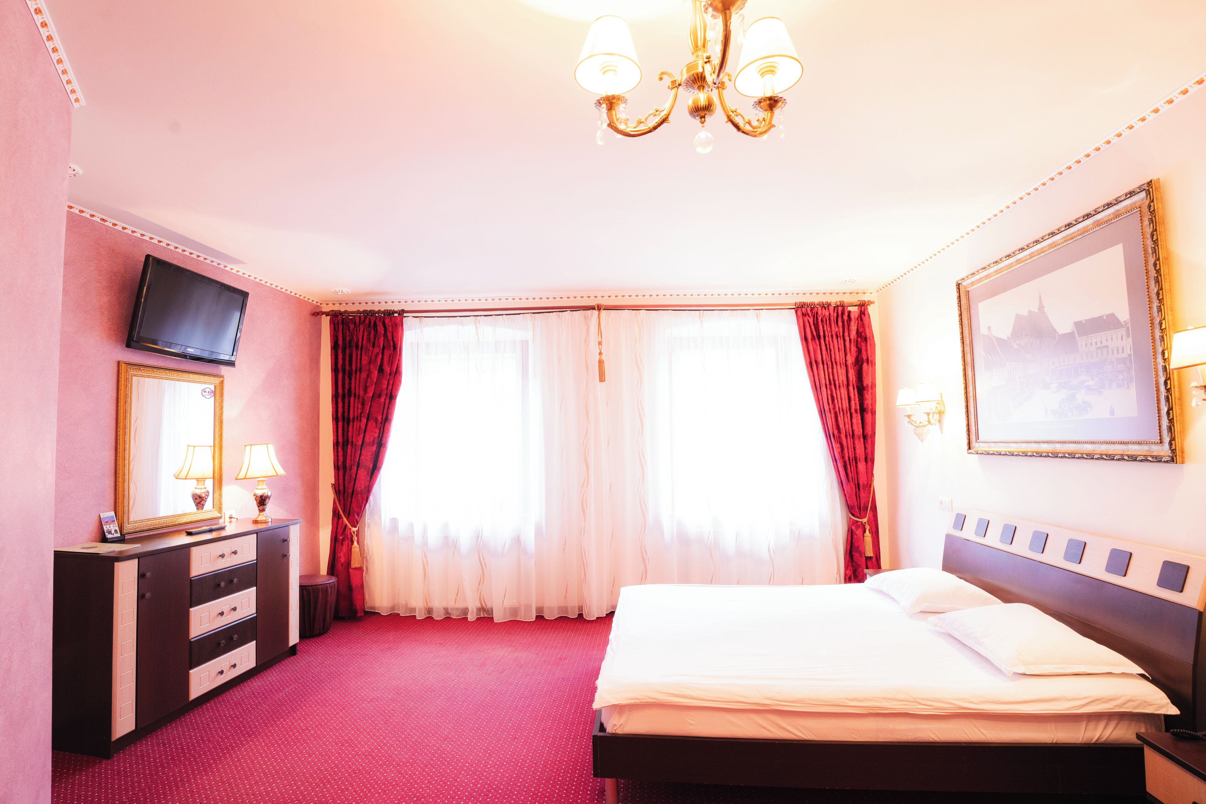 Una camera d'albergo con un letto, una televisione, un comò e un lampadario.