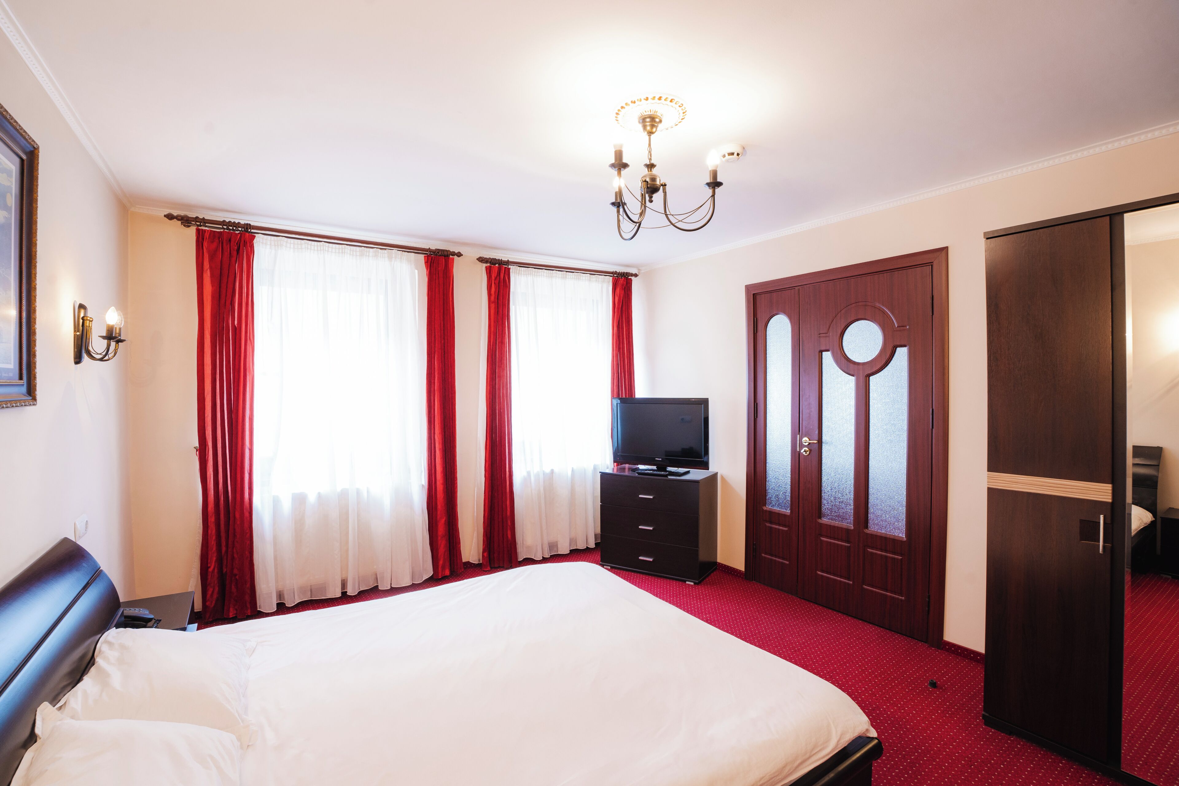 Una habitación de hotel con una cama grande, un televisor, un aparador y un armario.