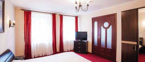 Una habitación de hotel con una cama grande, un televisor, un aparador y un armario.