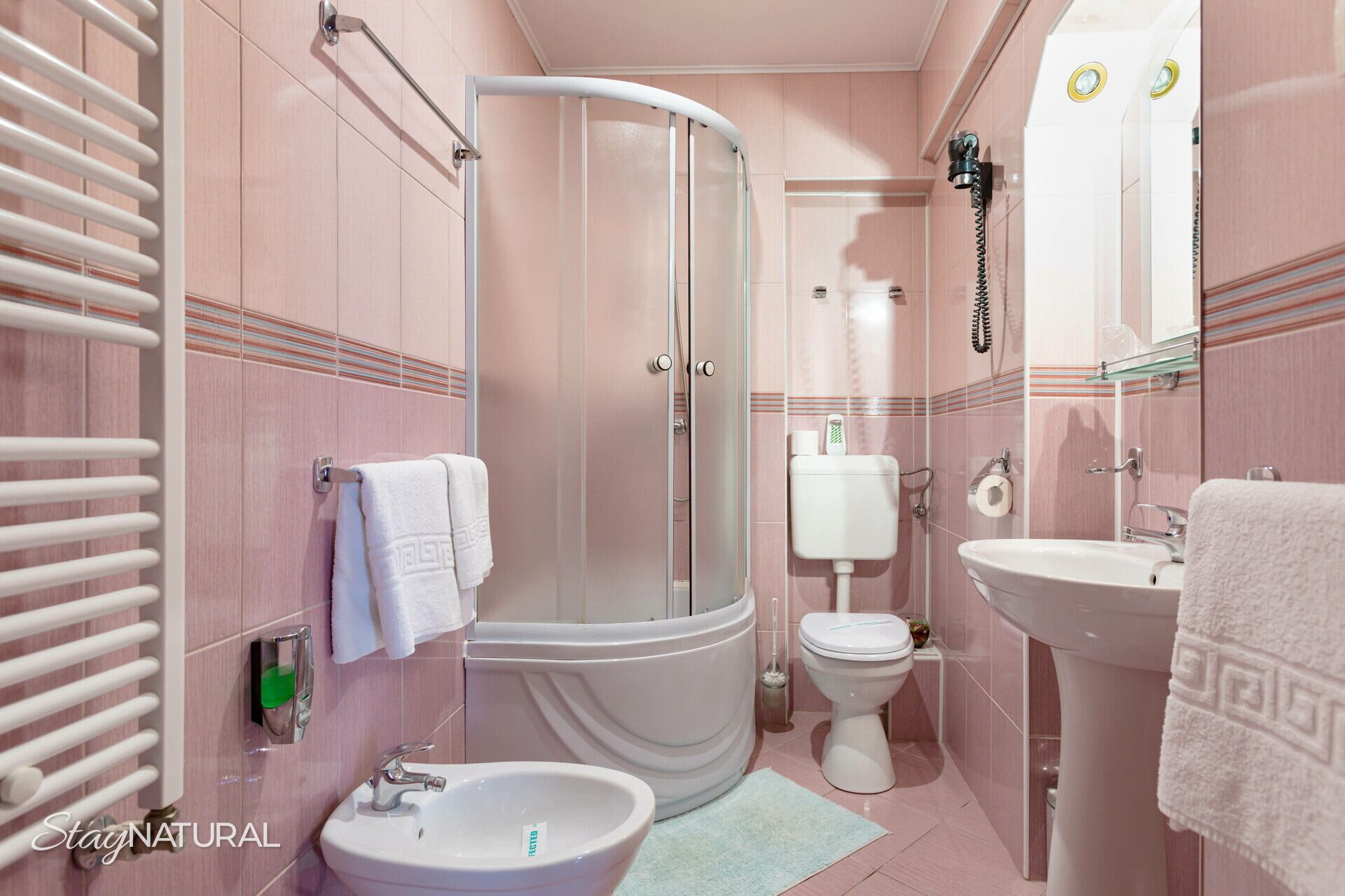 Ein Badezimmer mit Dusche, Toilette, Waschbecken und Handtuchhalter.