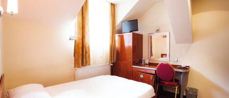 A hotel room with a bed, a desk, a chair, a television, and a window with curtains.