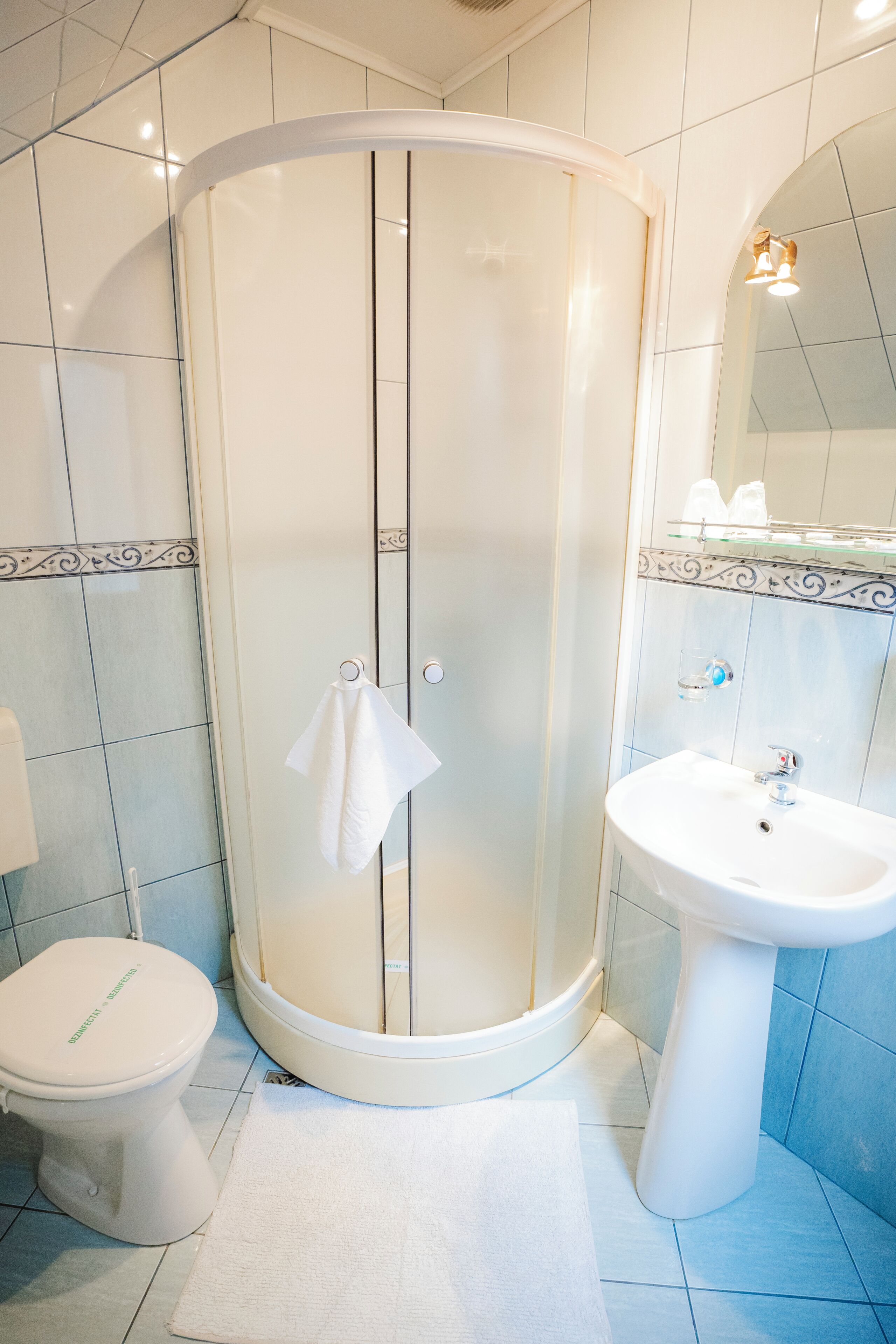 A bathroom with a shower enclosure, toilet, and sink.