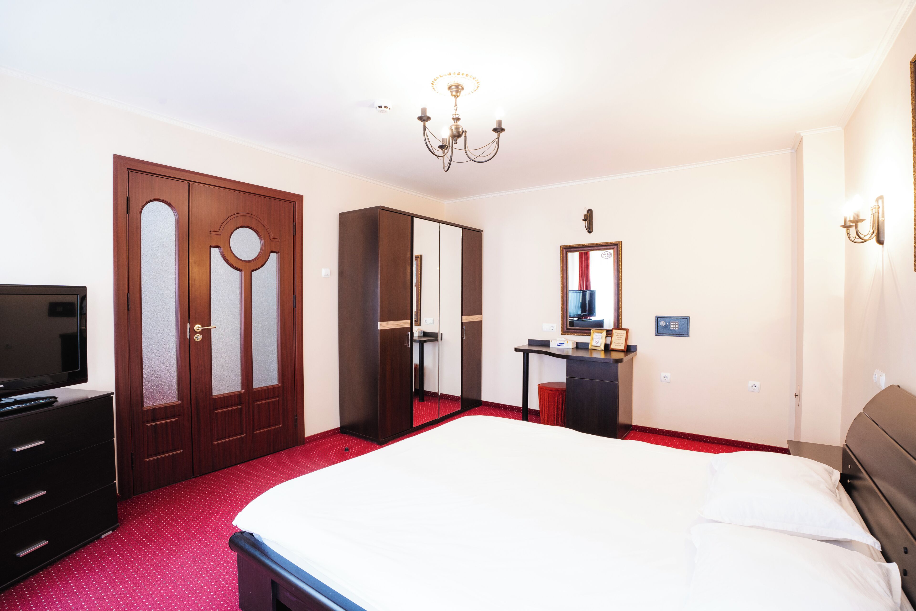 Una habitación de hotel con cama, escritorio, televisor y armario.