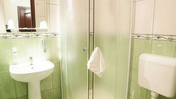 Un baño con lavamanos, inodoro y cabina de ducha.
