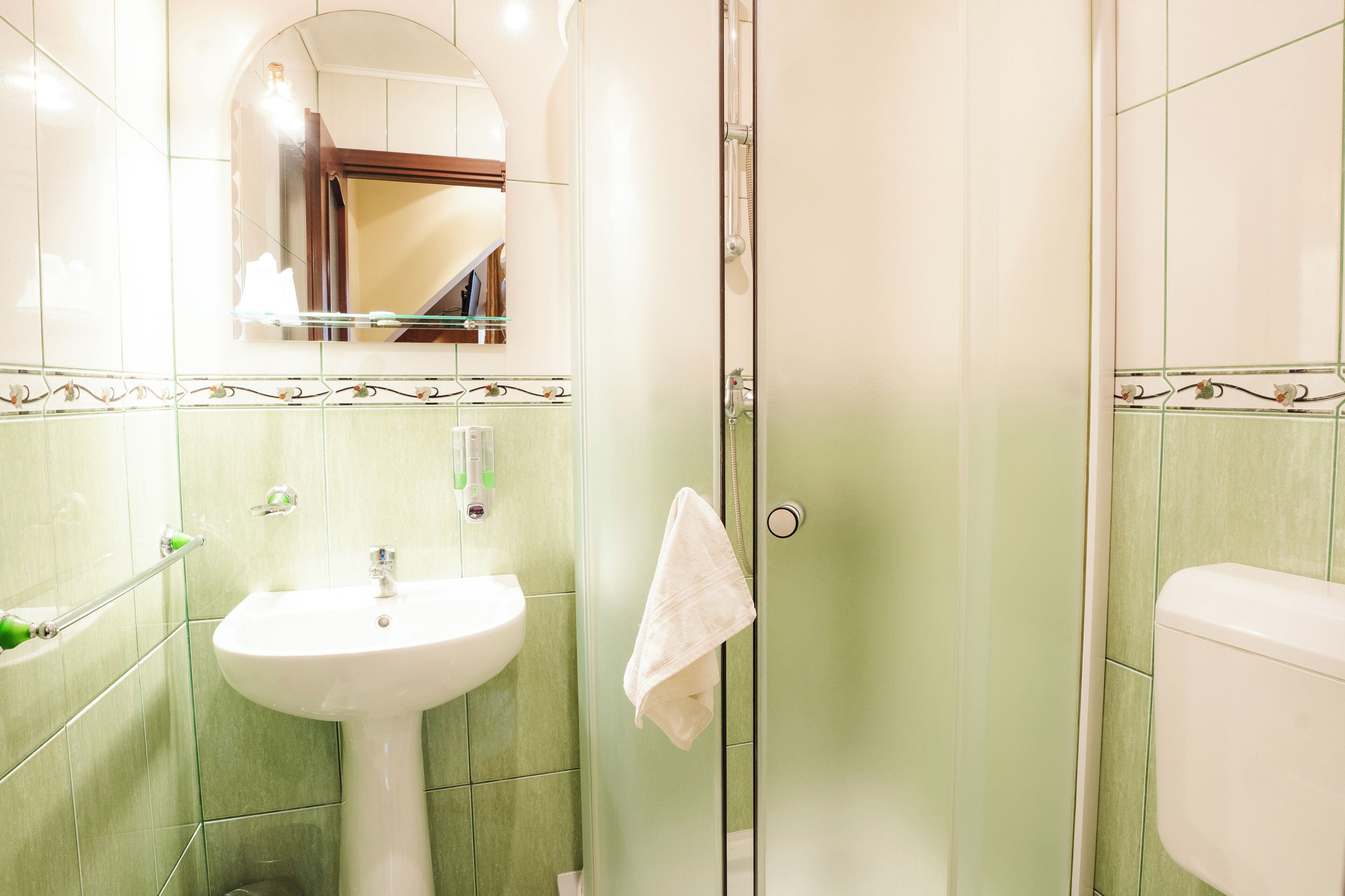 A bathroom with a sink, mirror, and shower.