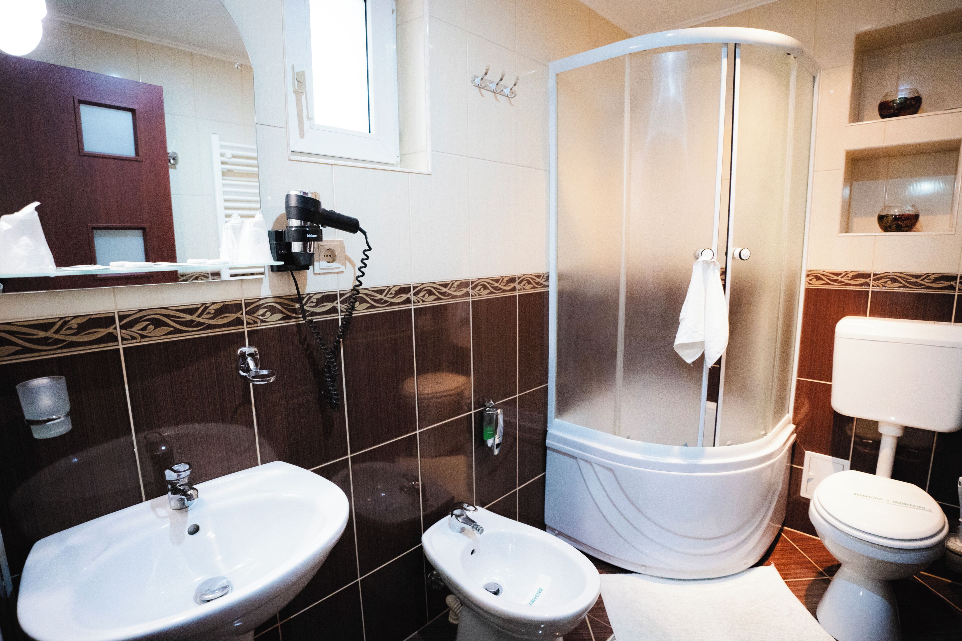A bathroom with a sink, bidet, toilet, and a shower enclosure.