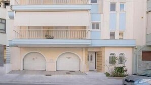 En flervåningsbostadsbyggnad med ett platt tak, en balkong på andra våningen och en garageport.
