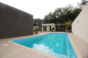 Ein Schwimmbecken mit Fliesen und einer umgebenden Gebäudeanlage mit dunkler Fassade und heller Wand.