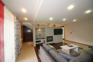 Ein Wohnzimmer mit einer Couch, einem Couchtisch, einem Kamin und einer Treppe, die zu einer anderen Etage führt.
