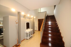 Eine Treppe führt zu einer zweiten Etage, ein weißer Konsolentisch mit Spiegel und eine Stehlampe befinden sich in einem Flur.