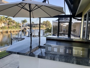 Ein moderner Außenbereich mit Sitzgelegenheiten, einem Pool, Sonnenschirm und Blick auf eine Marina.