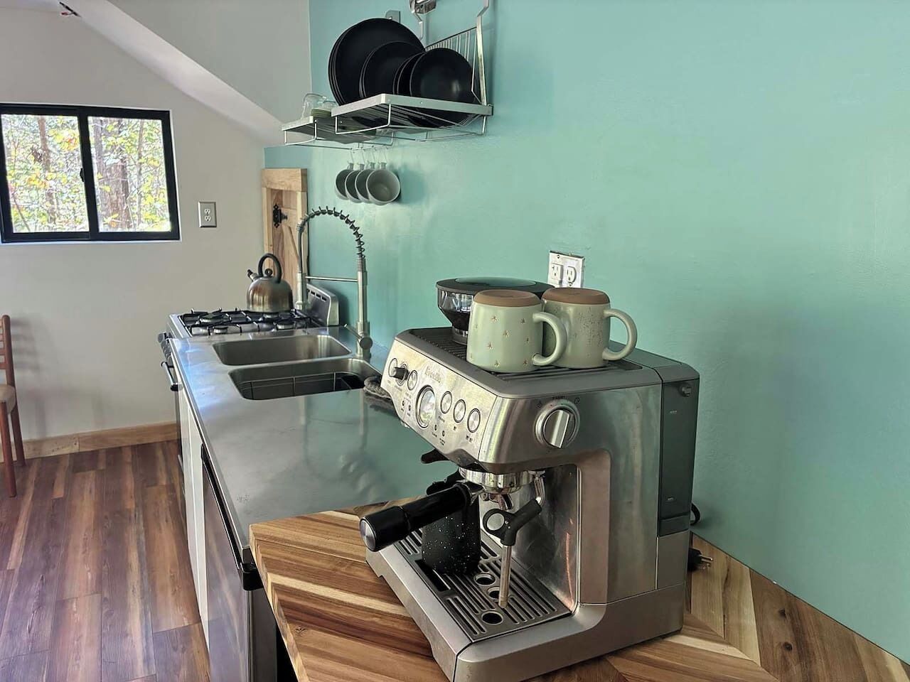 A kitchen with a stainless steel espresso machine, a gas stove, and a wooden countertop.