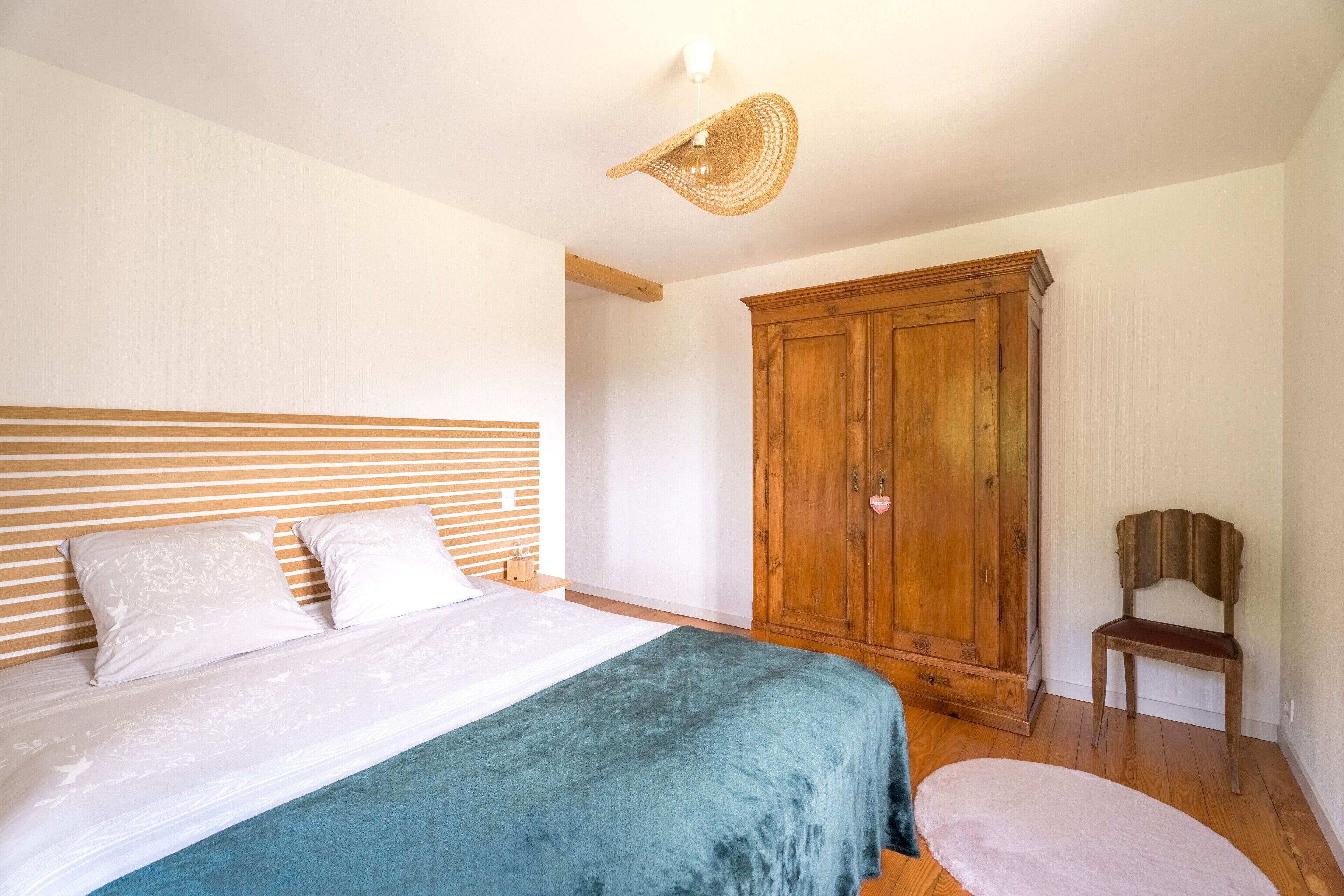 Een slaapkamer met een bed, een houten garderobe en een stoel.