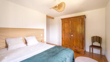 Een slaapkamer met een bed, een houten garderobe en een stoel.