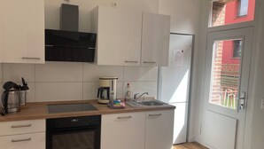 Ett modernt kök med vita skåp, en svart ugn, en kaffebryggare och en diskho.