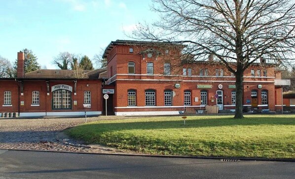 Ein Gebäude aus roten Ziegelsteinen mit Bogenfenstern und einem zentralen Eingang.