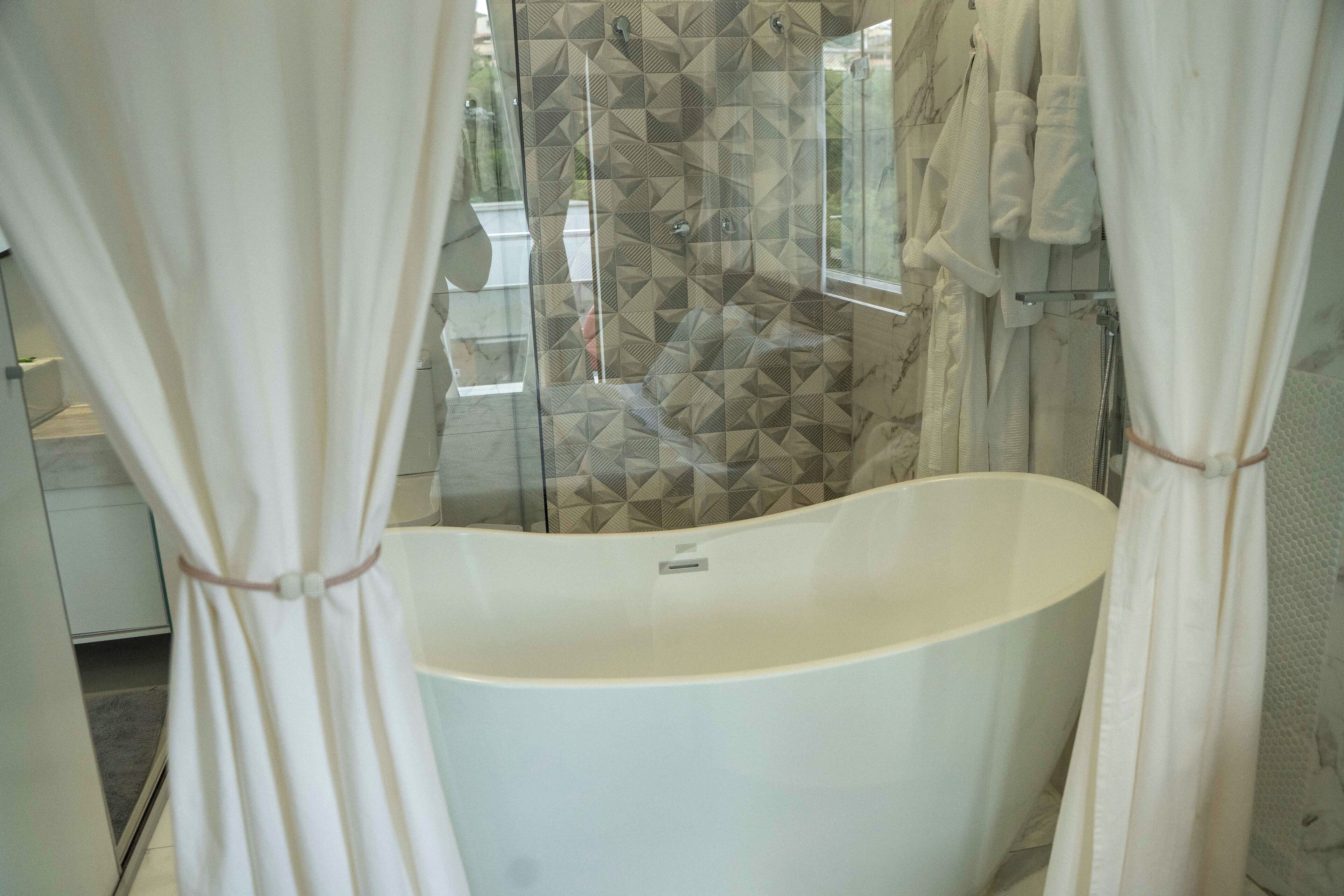 Un baño con bañera independiente, cabina de ducha con mampara de vidrio y un perchero para toallas.