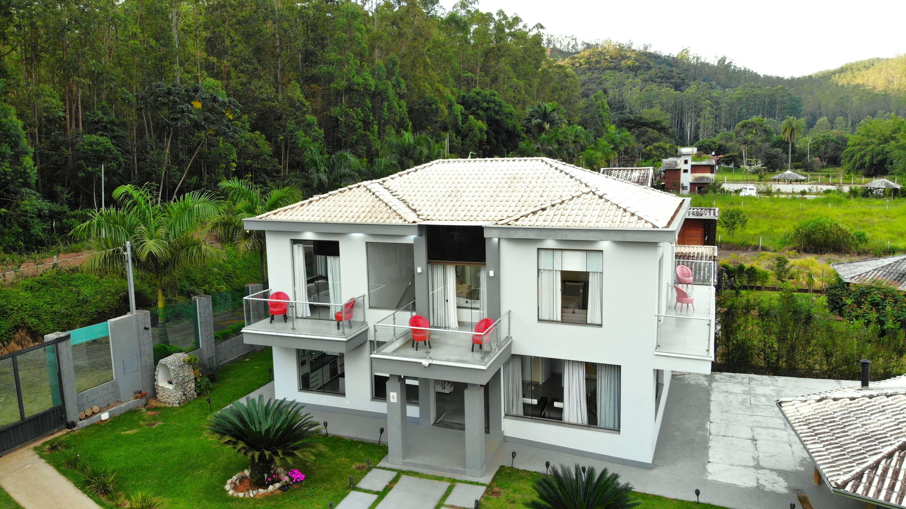 A two-story building with a balcony, large windows, and a garden area.