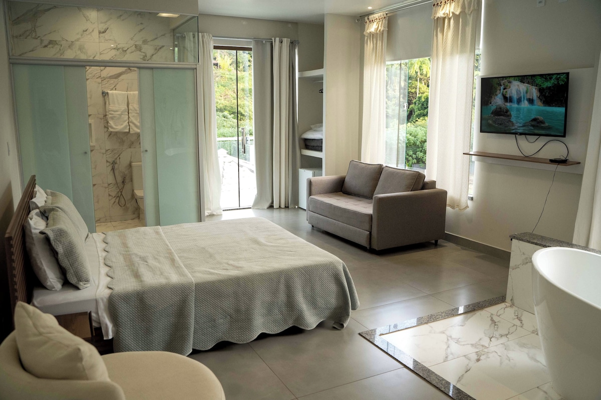 Een moderne hotelkamer met een groot bed, een bank, een televisie en een badkamer met een bad.