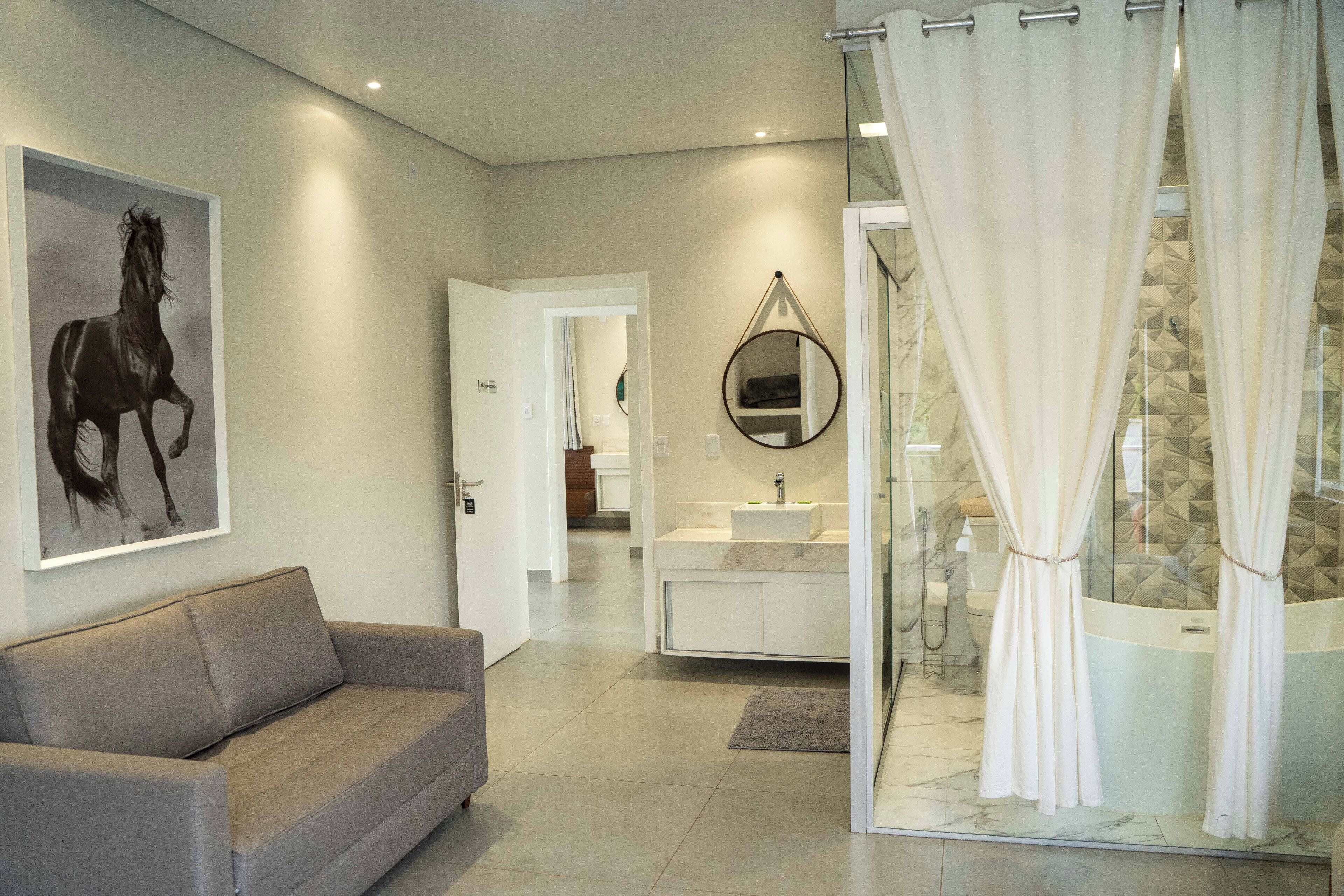 Une salle de bain moderne avec une douche, un lavabo et un miroir. Le salon est équipé d’un canapé beige.