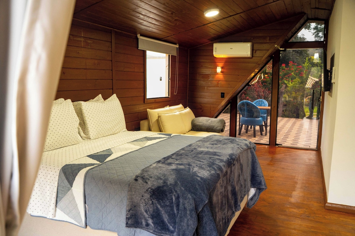 Een slaapkamer met een bed, kussens, een raam en uitzicht op het exterieur.