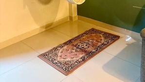 A room with a hanging hammock, a patterned rug, and framed artwork on the wall.