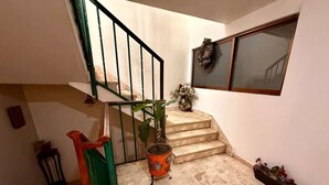 A staircase with a green railing, a potted plant, and a decorative wreath on the wall. - Dpto.sensillo, Foro Sol, GNP y Aeropuerto (Mexico City)